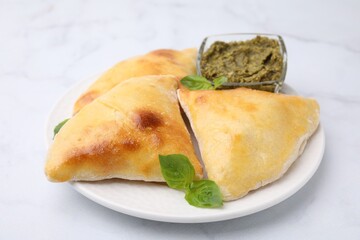 Delicious samosas with basil and pesto sauce on white marble table, closeup