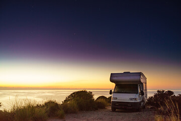 Camper vehicle on seashore at sunrise dawn