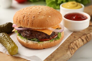 Tasty hamburger with patty, cheese and vegetables served on white table, closeup