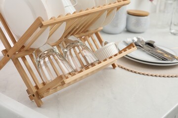 Fototapeta na wymiar Drying rack with clean dishes on light marble countertop in kitchen, closeup