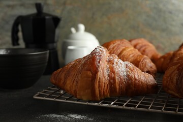 Delicious fresh croissants with powdered sugar on grey table