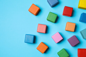 Blank colorful cubes on light blue background, flat lay. Space for text