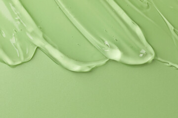 Clear cosmetic gel on light green background, top view. Space for text