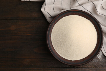 Uncooked organic semolina in bowl on wooden table, top view. Space for text