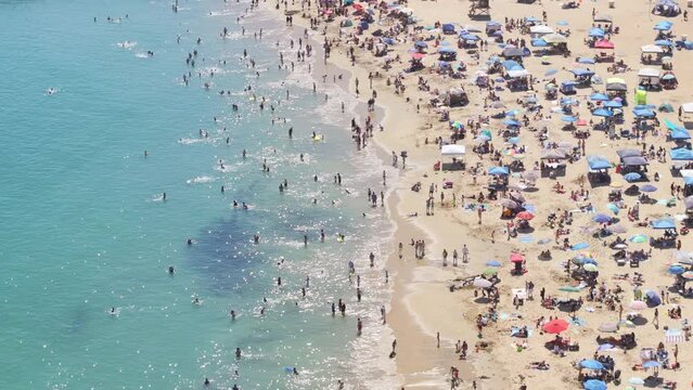 Drone flying over crowd of people sunbathing on beach of Corona Del Mar, Newport Beach, California, West coast, USA. Aerial view of Newport Bay full of tourists. People relaxing on beach at vacation 