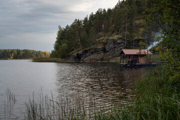 Fototapeta na wymiar A melted bathhouse on the shore of Lake Ladoga near the village of Lumivaara on a sunny autumn day, Ladoga skerries, Lahdenpohya, Republic of Karelia, Russia