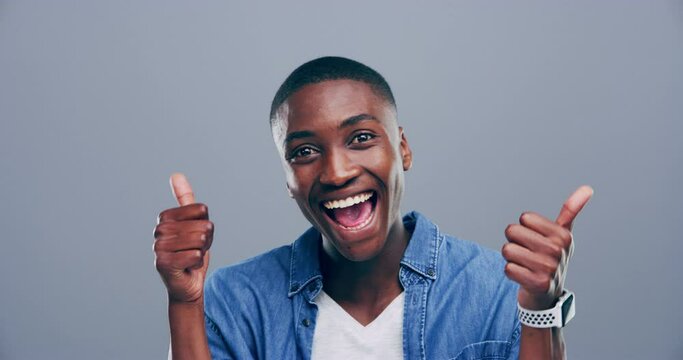 Black man, thumbs up and celebration for success, winning and excited with like emoji and vote in studio. Wow face of happy person or winner with yes hands, bonus and good news on a gray background