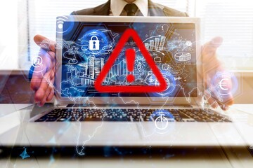 Businessman hands on laptop with warning sign.