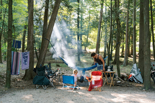 A horizontal image of a dad and his toddler daughter enjoying the calm setting of their campsite and campfire. 
