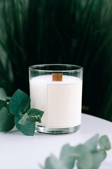 A scented candle with a clean empty label on the table. Mockup for the design of the cosmetic candle logo.