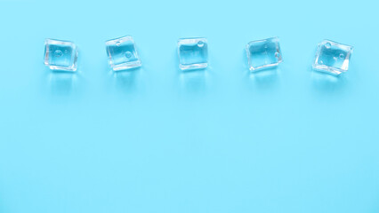 Concept of cold and refreshing. Ice cubes with water drops on a blue background.