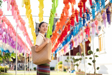 A beautiful Asian-Thai woman in a traditional dress is enjoying in a lantern festival at a temple.
