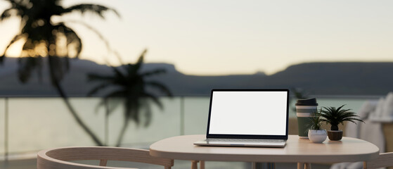 A laptop on a table at an outdoors terrace with an ocean view. Holiday, vacation, working remotely