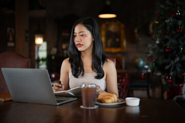 Young beautiful Asian woman working with laptop computer in a dark luxury living room.