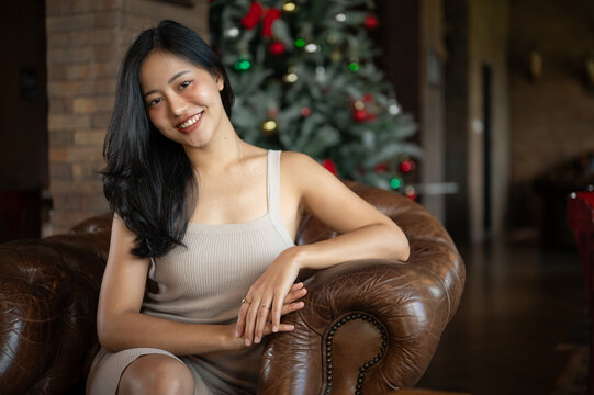 Young classy Asian woman sitting on vintage sofa in the luxury and fancy living room.