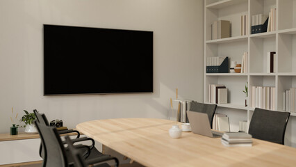 A large TV mockup screen on a white wall in a modern, minimalist meeting room. place of work