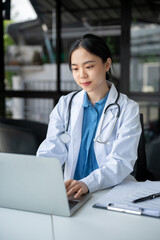 A professional doctor is working on her laptop at her desk, checking medical cases online.