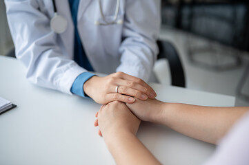 A doctor holding a patient's hands to comfort and reassure them during a medical checkup.