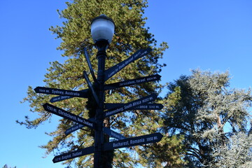 Light pole with multi directional signs pointing to major cities across the globe.