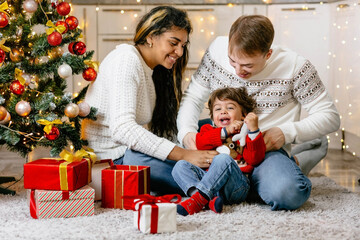 Christmas Eve gifts for children from Santa. Parents give a small gift to the baby at the Christmas tree