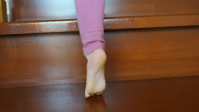 Closeup of little girl foot going up the stairs at home, child climbing stairs