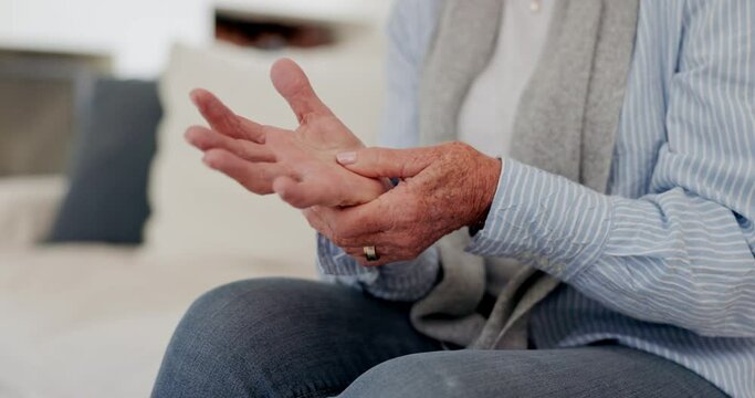 Hands, arthritis or carpal tunnel with a senior person on a sofa in the living room of a retirement home closeup. Wrist pain, osteoporosis or fibromyalgia with an elderly adult in an apartment