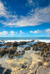 Blue waters surge and splash against a rocky shore