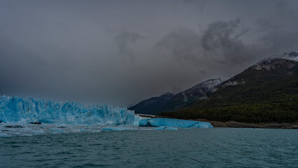 Beautiful blue glacier Perito Moreno in turquoise lake. A wall of cracked ice rises above the...