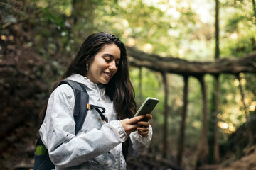 Cheerful woman using smartphone in the jungle