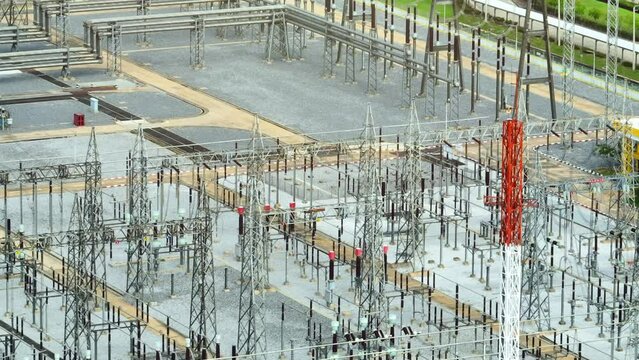 Majestic and imposing, the high voltage power station stands as a modern marvel, a symphony of towering transformers, humming with electrifying energy, seen from above by a drone's watchful eye.
