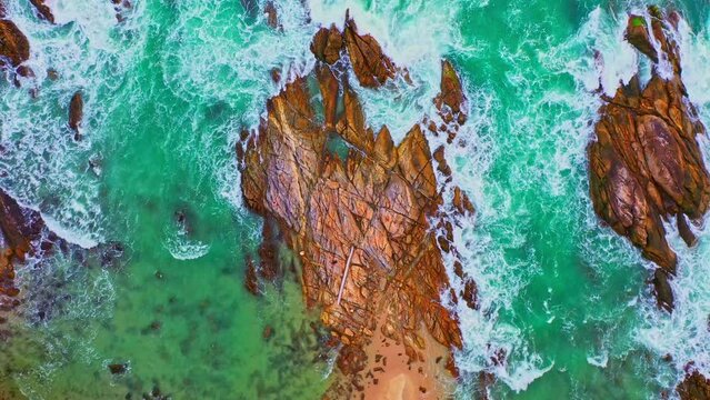 aerial top view White foam waves in the green sea lapping on the large rock kat Kalim beach..Wave after wave swept towards the shore..beautiful green sea background.
