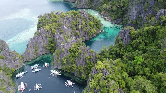 Clear blue water of twin lagoon amid towering karst and lush tropical foliage, Coron