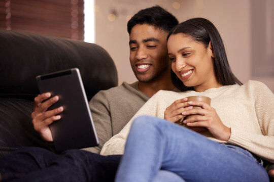 Love, relax and couple with tablet on sofa for social media, movies or streaming film at home together. Happy, smile or people in living room with digital, app or video search in a house with coffee