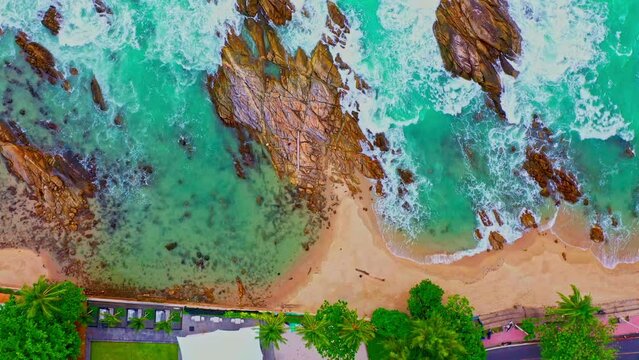 aerial top view White foam waves in the green sea lapping on the large rock kat Kalim beach..Wave after wave swept towards the shore..beautiful green sea background.