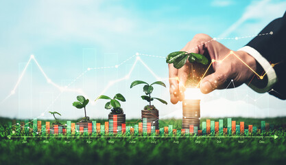 Businessman plant seedling on top of growing coin stack on sky background as ESG investment with...