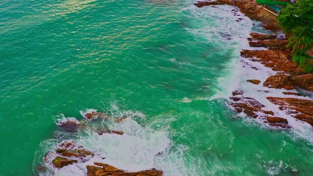 aerial top view White foam waves in the green sea lapping on the large rock kat Kalim beach..Wave after wave swept towards the shore..beautiful green sea background.