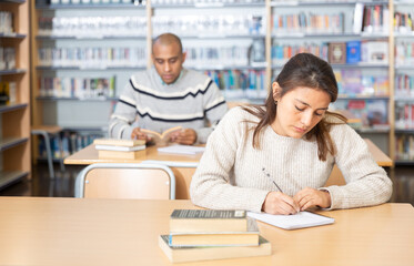 Adult female student working in library, concept of adult education