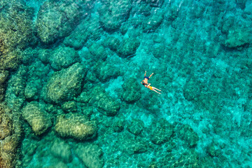 Aerial view of a young couple snorkeling above coral reef reaching deeper parts of the crystal...