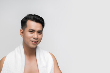 Young smiling man with towel on shoulders posing isolated over white studio wall