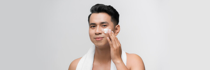 smiling man applying cream lotion on face