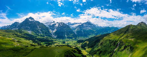 Fototapeta na wymiar Grindelwald view and summer Swiss Alps mountains panorama landscape, green fields and high peaks in background, Switzerland, Bernese Oberland, Europe.