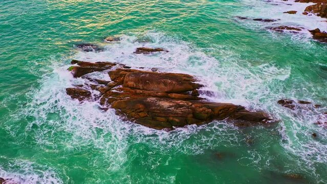 aerial top view White foam waves in the green sea lapping on the large rock kat Kalim beach..Wave after wave swept towards the shore..beautiful green sea background.
