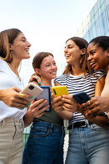 Vertical portrait of happy multiracial group of young women friends laughing and having fun while...