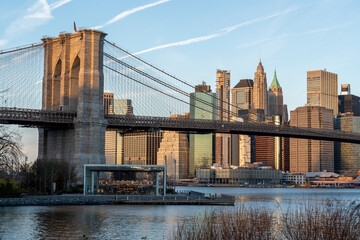 brooklyn bridge with manhattan skyline in the background in the morning hours with soft sunlight
