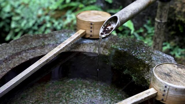 Japanese Water Fountain With Bamboo Ladles Resting On Side. Close Up, Slow Motion Shot