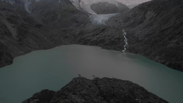 Aerial view of the Gauli glacier in the Bernese Oberland region of the Swiss Alps with a panning view from the lake towards the glacier on a cloudy.