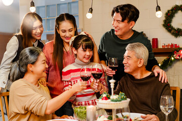 Happy and cheerful Asian family talking and smiling during Christmas dinner at home. Celebrate the holiday together Family reunions and reunions. Daughter is surrounded by warm family members.