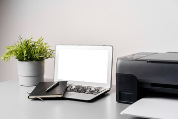 Printer and laptop on grey table in office
