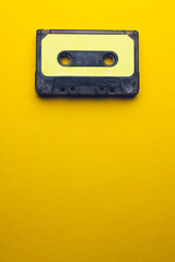 Overhead view of black and yellow cassette tape with copy space on yellow background