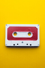 Overhead view of red and white cassette tape with copy space on yellow background